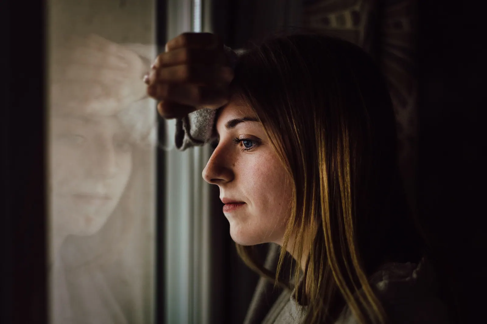 A woman looking out of a window, lost in thought